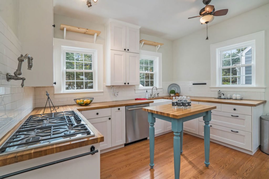 Kitchen shows 5-burner cooktop and butcher block counters